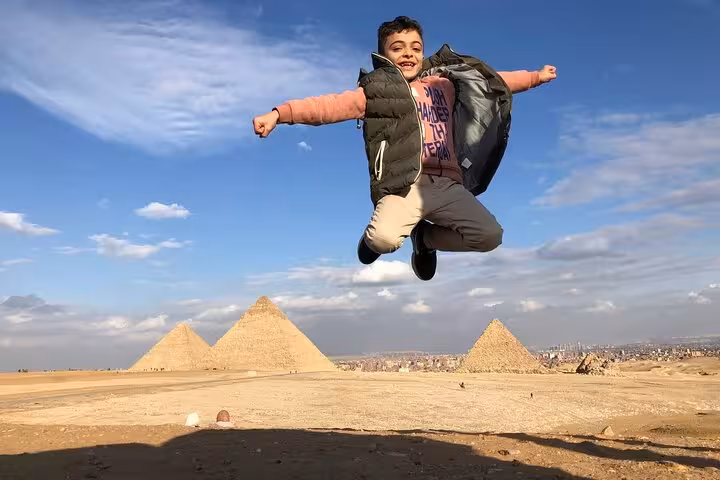 Boy jumping with panoramic view of the Giza Pyramids, Egypt private tour with camel ride and photos