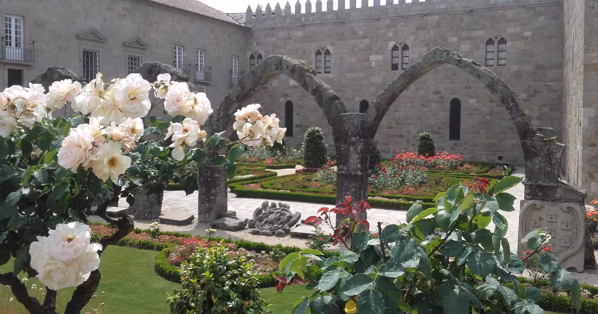 Flower-filled courtyard at Braga Cathedral on a half-day small-group tour, with medieval stone arches and gardens