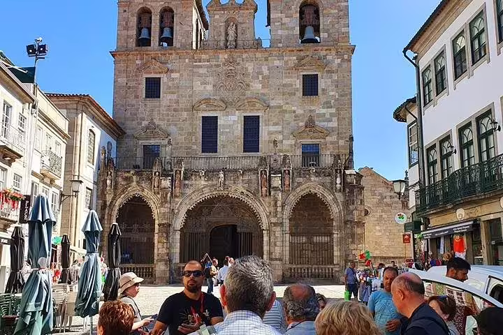 Tourists gather in front of Braga Cathedral, showcasing its stunning medieval architecture on a sunny day.