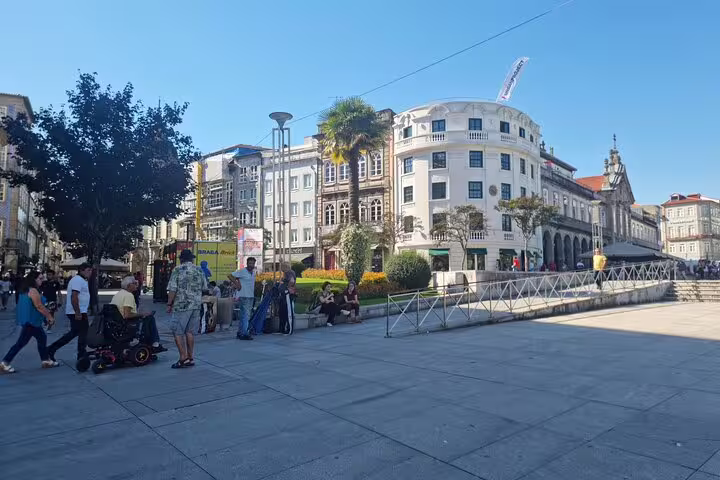 Vibrant Braga city square bustling with people, historic architecture, and lush greenery on a sunny day.