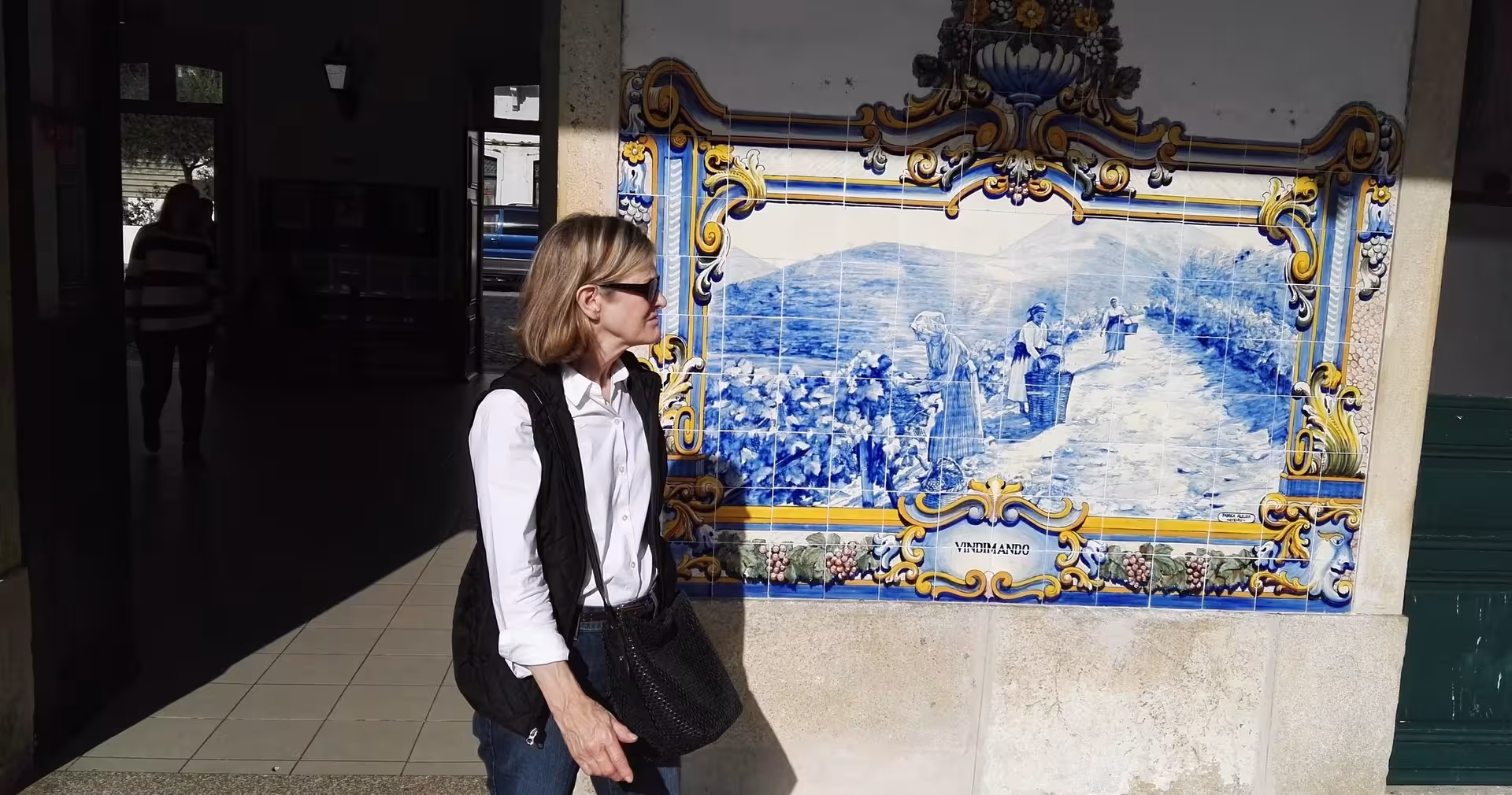 Traveler viewing traditional azulejo wine-harvest mural stop on Braga to Douro Valley small-group tour