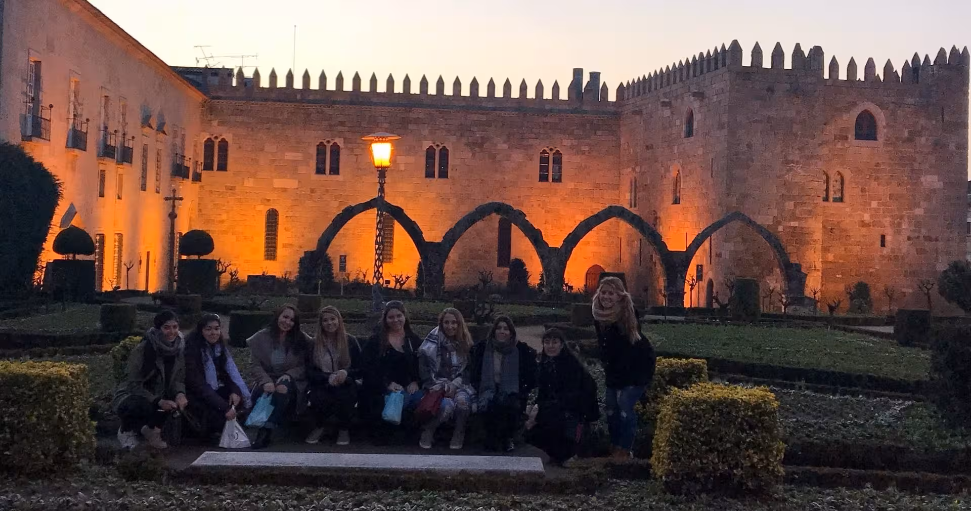 Small-group Braga food tour guests pose in a historic courtyard at dusk, Portugal lunch experience