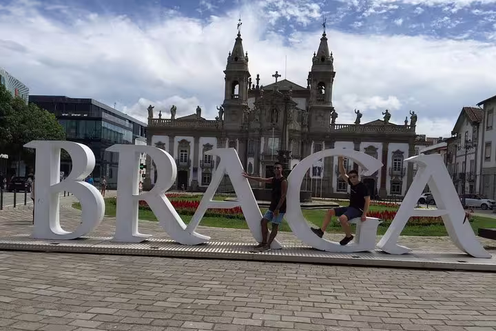 Tourists posing with the large Braga sign in front of the historic baroque church, a vibrant highlight of the city.