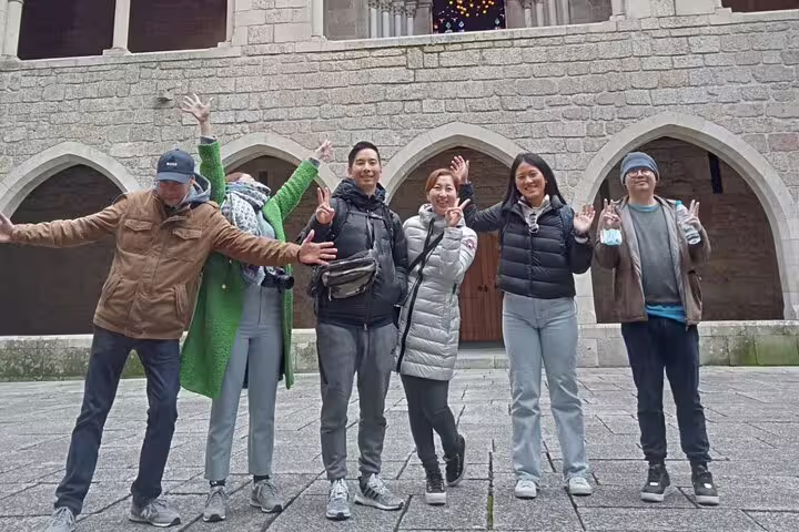 Smiling group of tourists posing at a historic stone courtyard in Guimarães during a full-day small group tour.