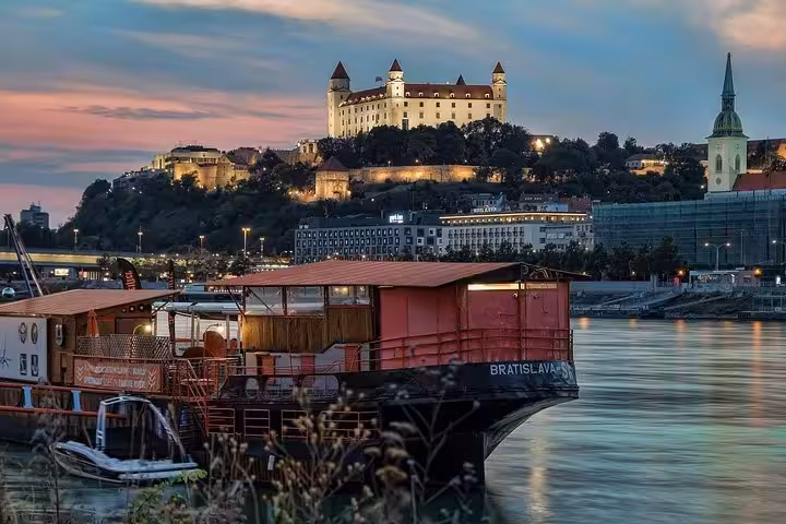 Danube riverboat with Bratislava Castle at sunset, highlight of a private Bratislava day trip from Vienna