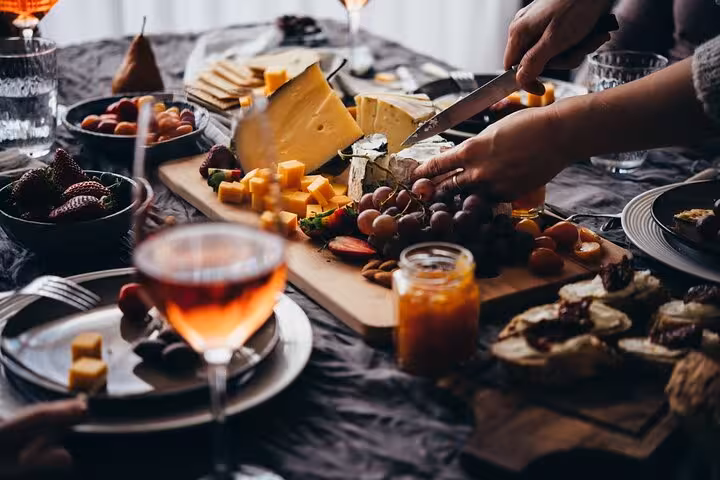 A vibrant Brazilian cheese and fruit platter being prepared, featuring cheeses, grapes, and strawberries for a gourmet experience.