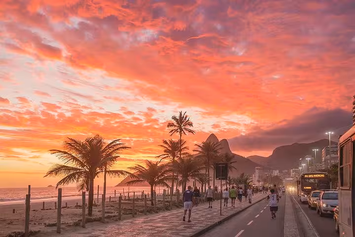 Vibrant sunset over Ipanema Beach with palm trees and people strolling, capturing the lively Rio de Janeiro atmosphere.