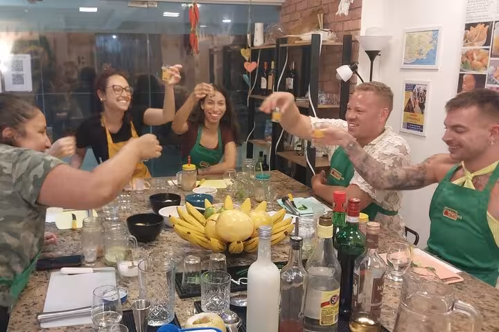 Group of friends toasting at a Brazilian cocktail class on Ipanema Beach, surrounded by vibrant fruits and spirits.
