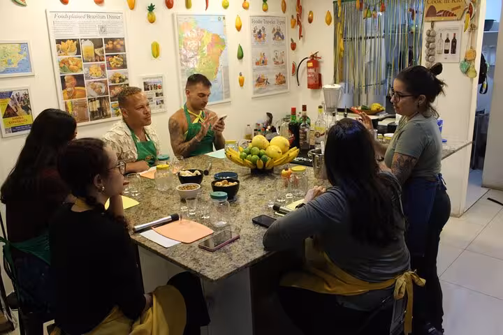 Participants gathered around a table learning Brazilian cocktail making in a lively, colorful kitchen setting.
