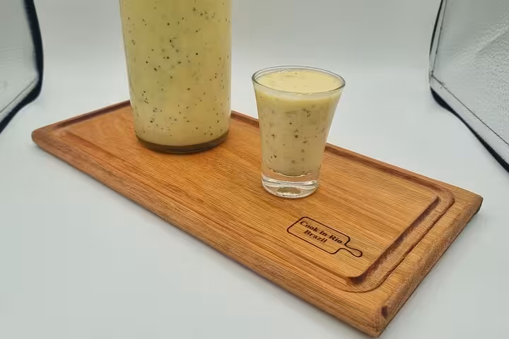 Refreshing Brazilian cocktail in a bottle and shot glass on a wooden board, perfect for Ipanema Beach sunsets.