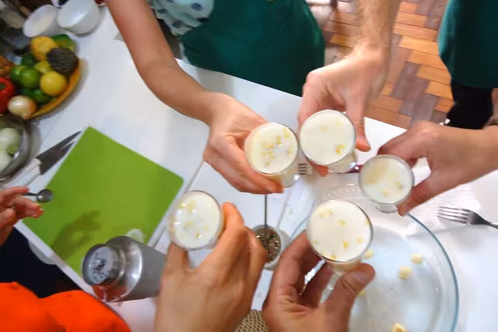 Group toasting with Brazilian cocktails in a lively Ipanema Beach setting, surrounded by fresh ingredients.