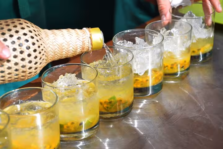 Traditional Brazilian cocktails being poured with passion fruit and ice on Ipanema Beach at sunset.