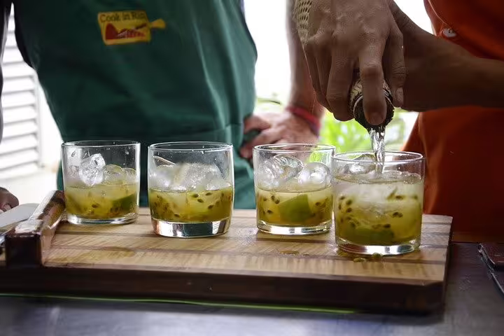 Participants crafting Brazilian cocktails garnished with ice and passion fruit at a Rio de Janeiro cooking class.