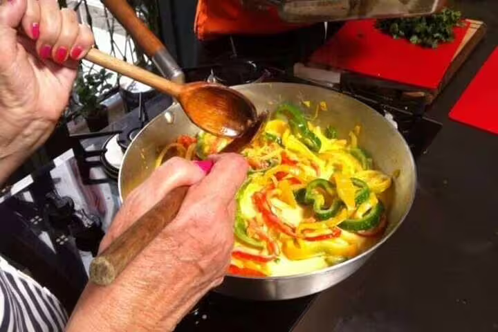 Hands skillfully prepare colorful Brazilian dish with peppers during a cooking class in Rio de Janeiro.