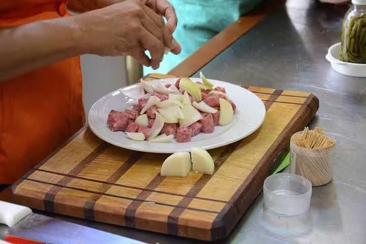 Preparing a plate of diced meat and onions on a wooden board during a Brazilian cooking class in Rio.