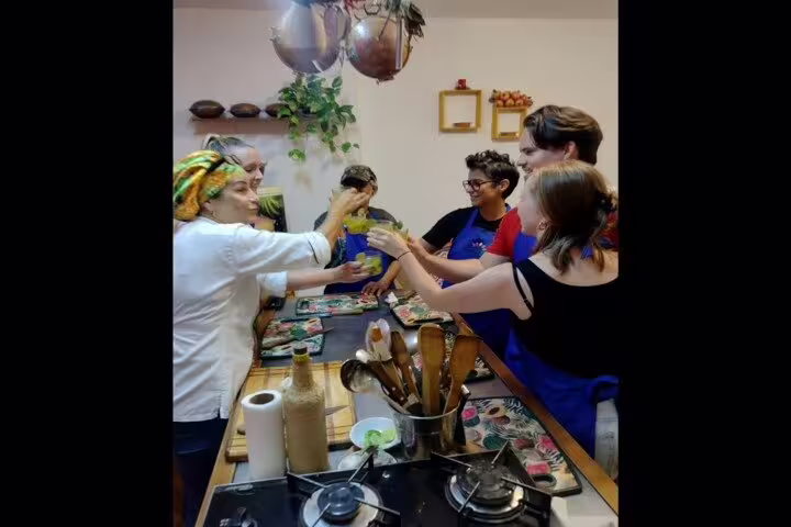 Group of participants toasting drinks at a vibrant Brazilian cooking class in Rio de Janeiro kitchen.