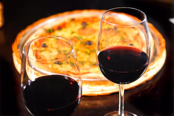 Two glasses of red wine paired with a pizza at a traditional Brazilian diner with live music.