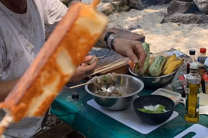 Outdoor seafood cooking class in Rio featuring skewers, tropical fruits, and essential ingredients on a beachside table.