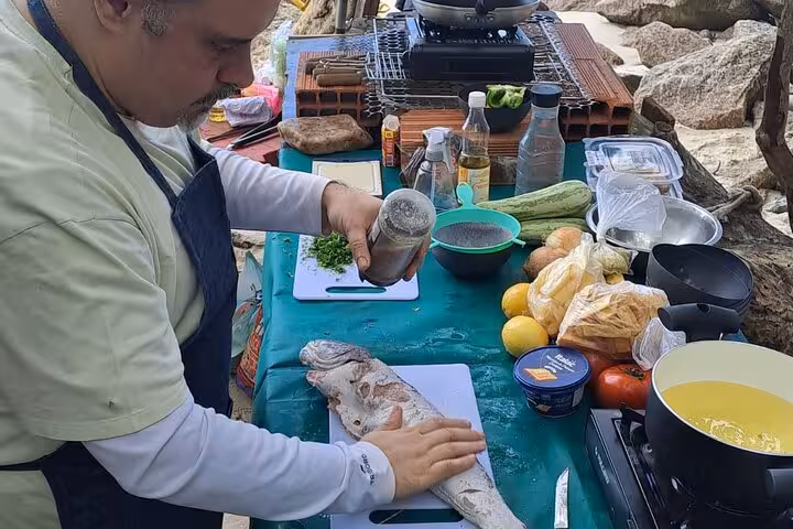 Man seasoning fresh fish at an outdoor cooking station, ideal for a hands-on seafood class in Rio.