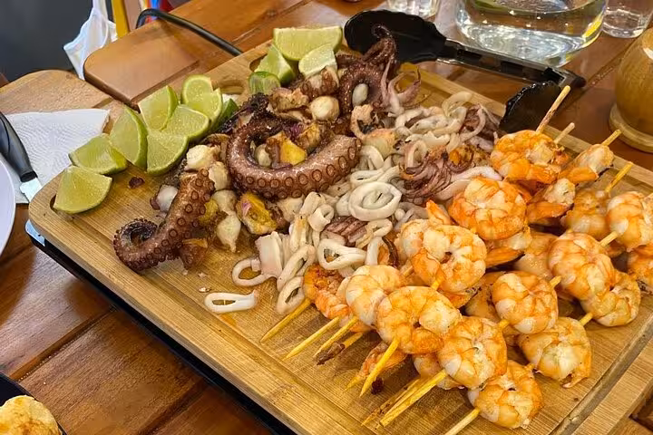 Grilled seafood platter with shrimp skewers, octopus, and lime wedges, highlighting Rio's culinary delights.