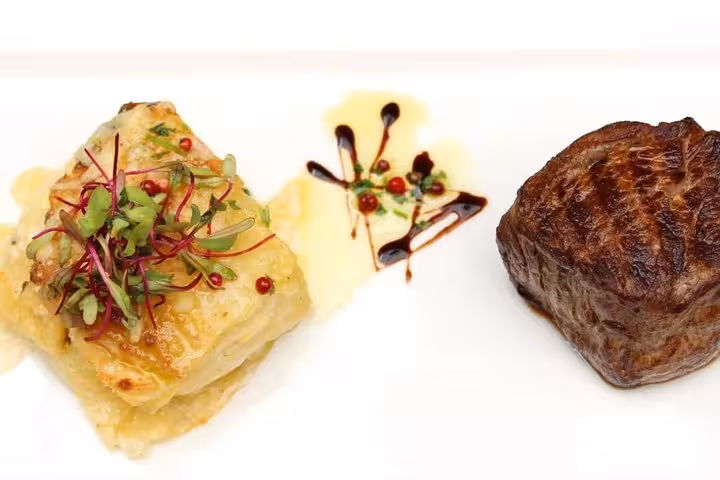Gourmet Brazilian steak and lasagna garnished with microgreens and sauce on a white plate.
