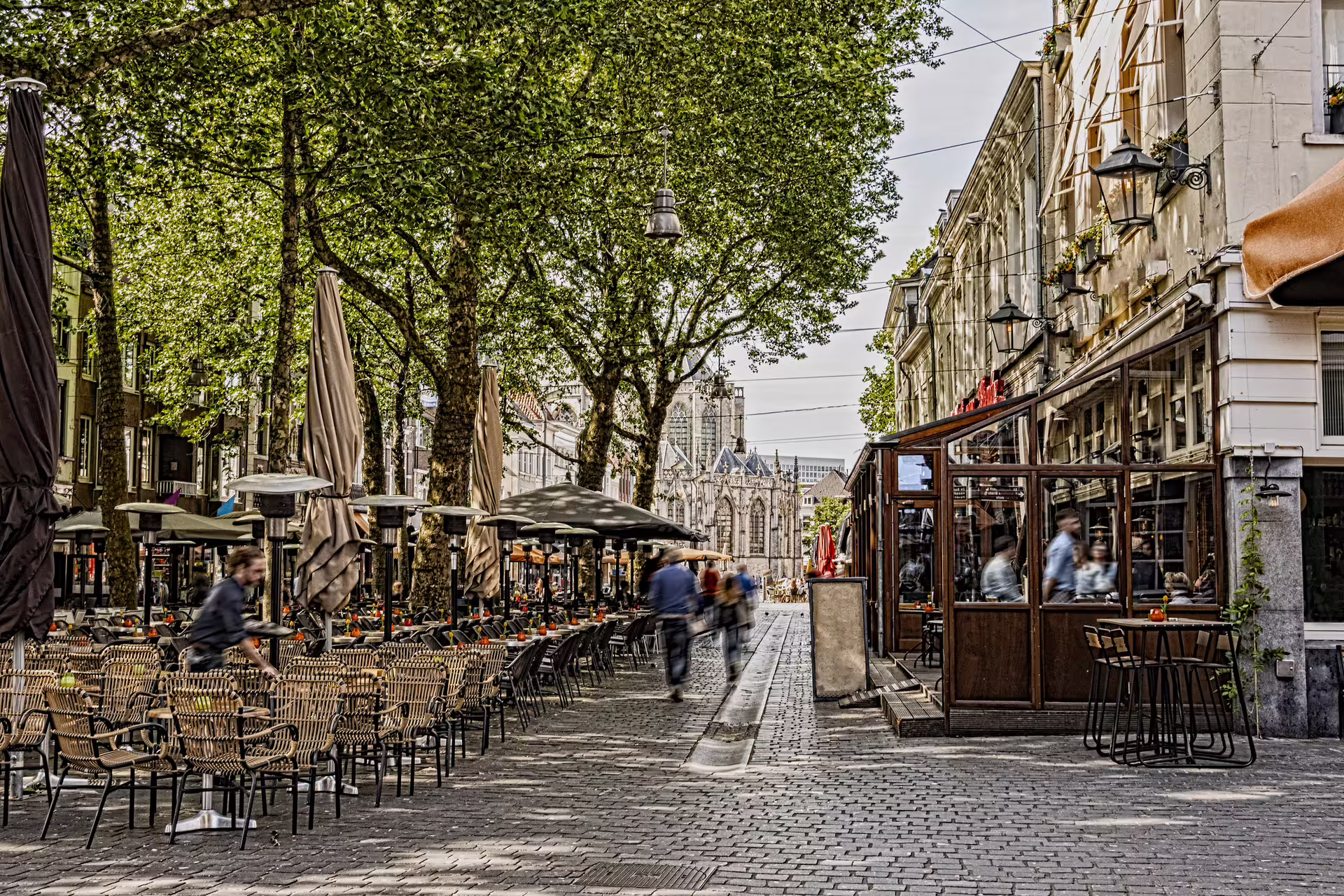 Terrace cafés on Breda’s Grote Markt with church view, explored on a self-guided 1-day walking tour audioguide