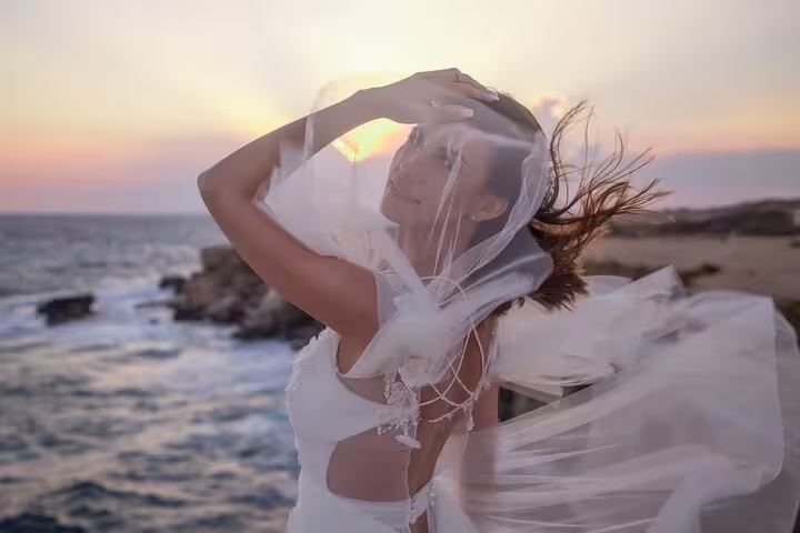 Bride in flowing gown poses gracefully against a stunning Ayia Napa sunset during a private beach photoshoot.