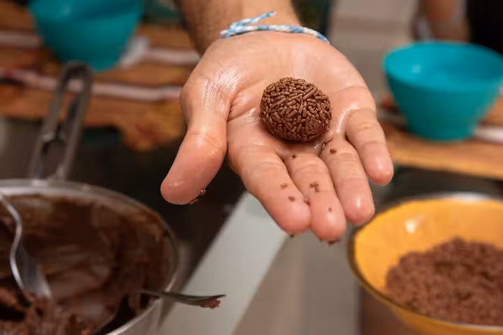 A hand displaying a freshly made brigadeiro during a Bahian dessert cooking class experience.