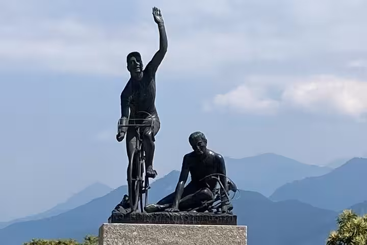 Bronze cyclist statue in Como with Alps backdrop, scenic photo stop on Lake Como and Bellagio day trip from Milan