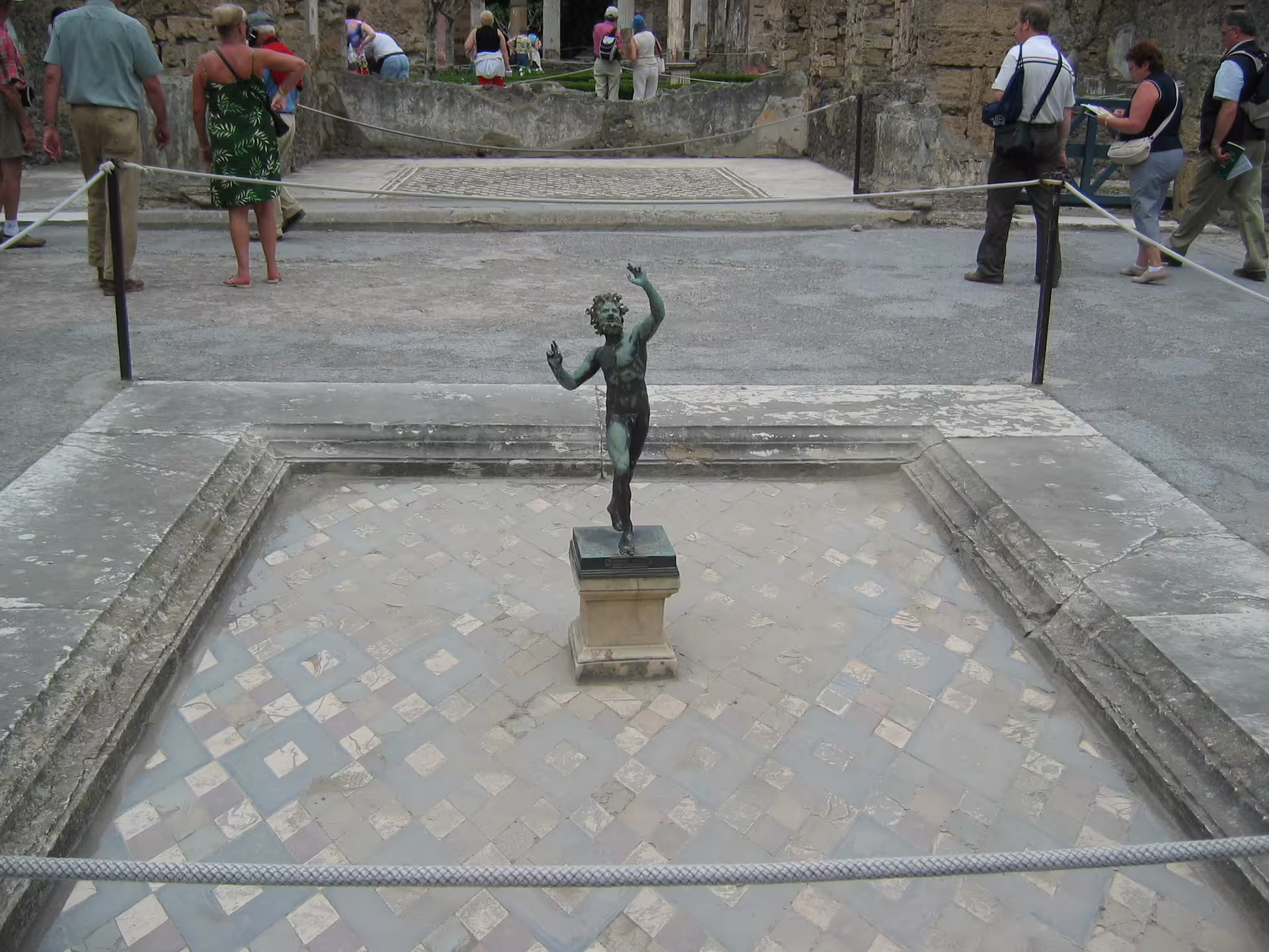Bronze dancing statue in Pompeii courtyard with tourists, included on low cost Pompeii and Vesuvius from Naples