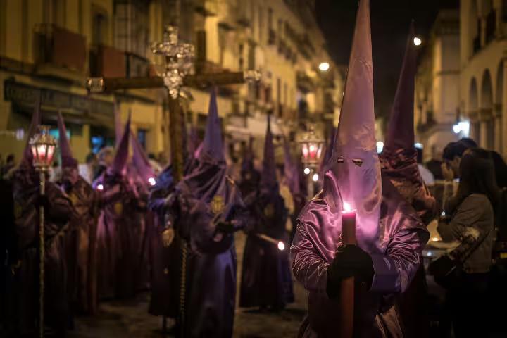 Hooded figures with candles during a traditional Holy Week procession in Seville, Spain, part of a private tour experience.
