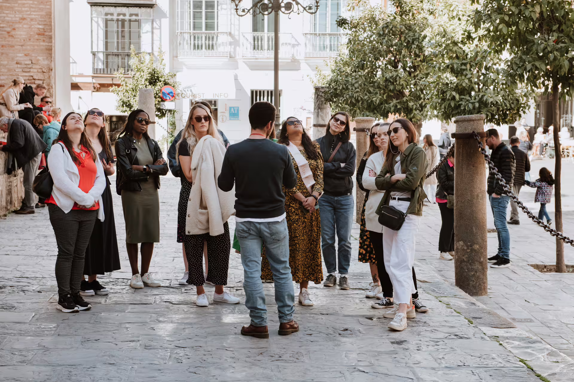 A diverse group of tourists listens attentively to a guide during a private walking tour in the historic streets of Seville.