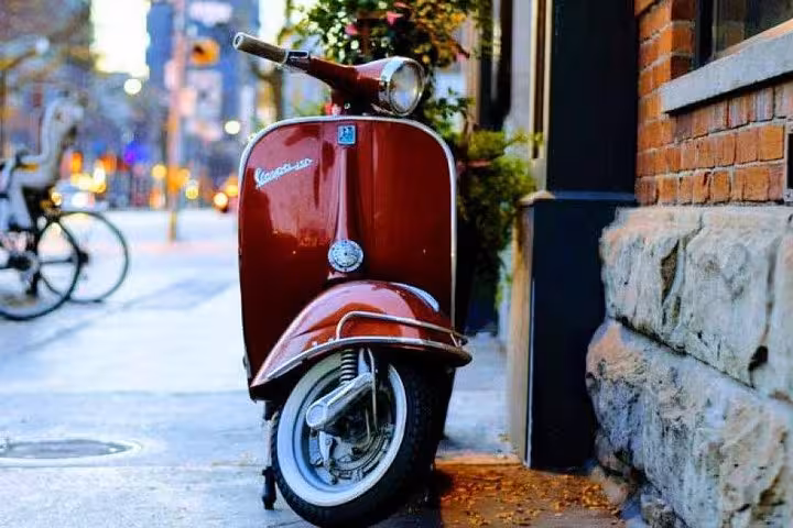 Classic brown Vespa leaning against a brick wall in Florence, ready for a scenic Italian city ride.