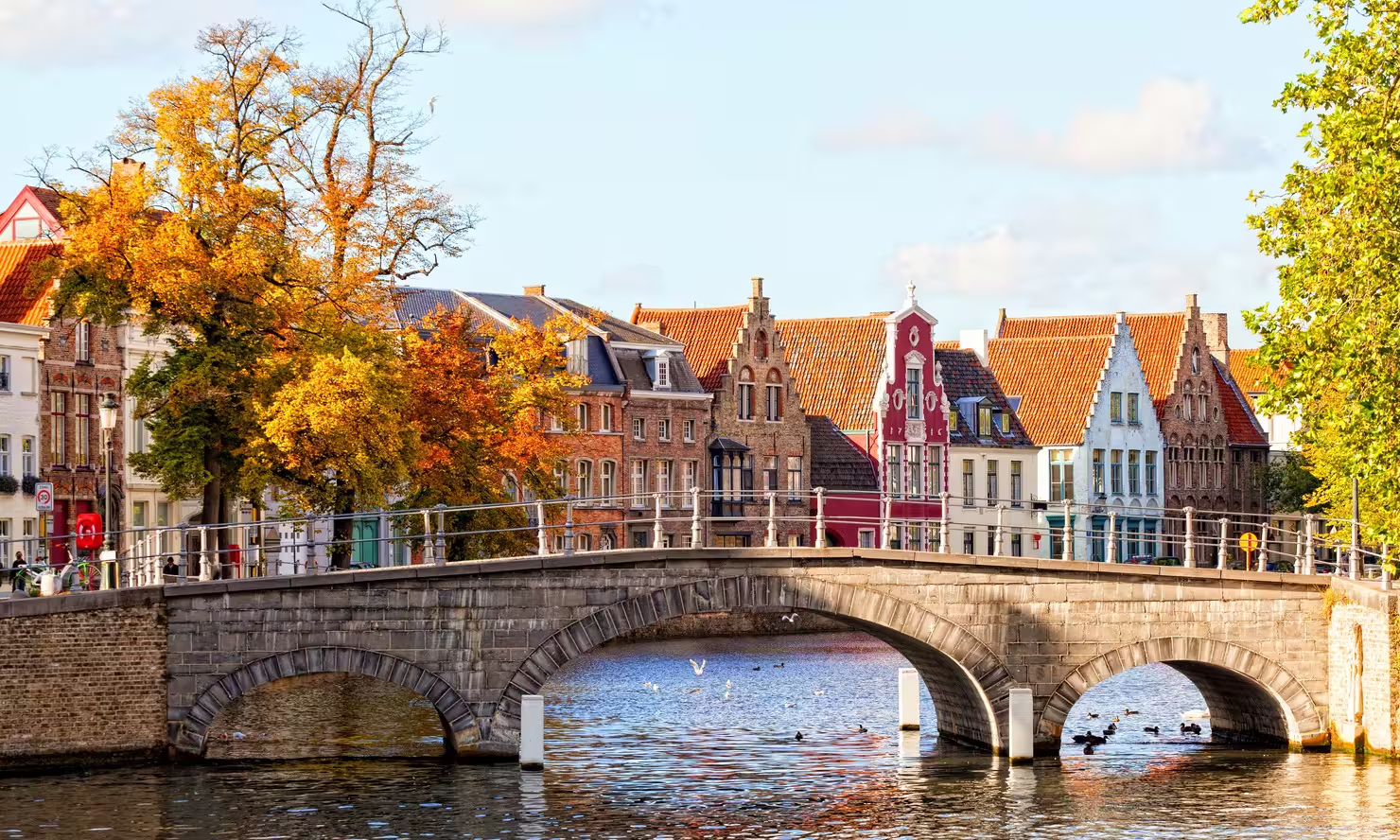 Stone bridge over Bruges canal with colorful gabled houses, highlight of a Bruges in 1 day audio walking tour