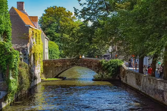 Scenic canal view in Bruges featuring a charming stone bridge and lush greenery, perfect for a private walking tour in Flanders.