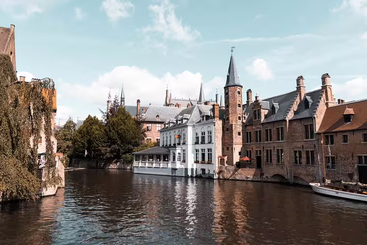 Scenic view of Bruges' historic canals and medieval architecture on a sunny day, perfect for a private day trip from Brussels.