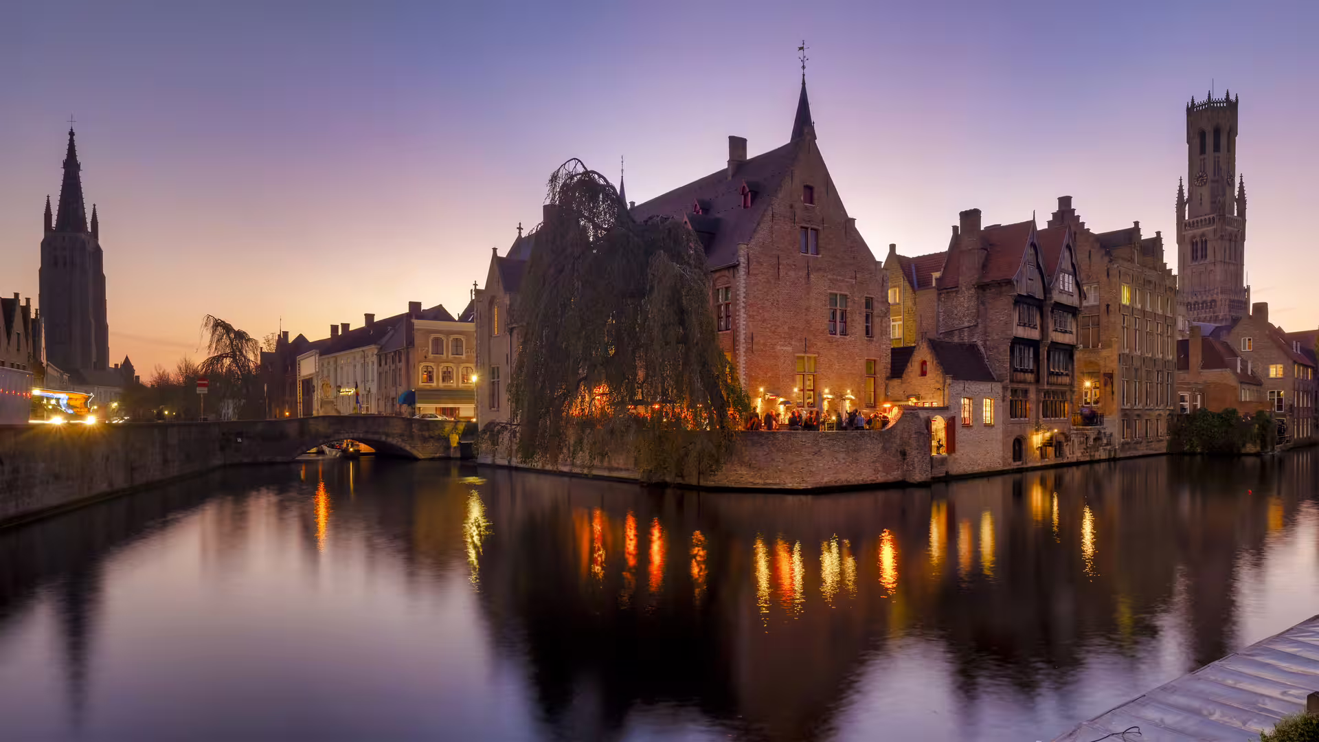 Bruges canals at sunset with medieval skyline, ideal for a 1-day walking tour audioguide in 7 languages