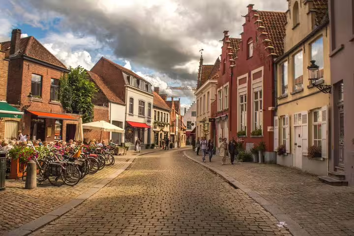 Charming medieval street in Bruges with colorful historic buildings and outdoor cafes, perfect for a private day trip from Brussels.