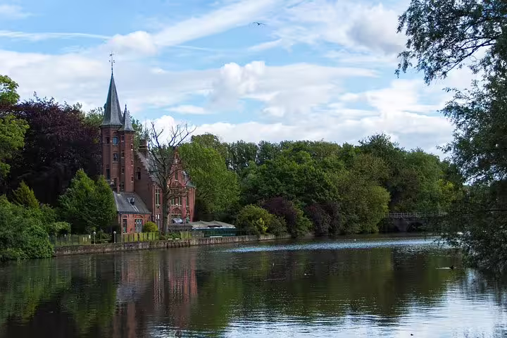 Scenic view of Bruges' Minnewater Lake with historic architecture and lush greenery, ideal for a private day trip from Brussels.