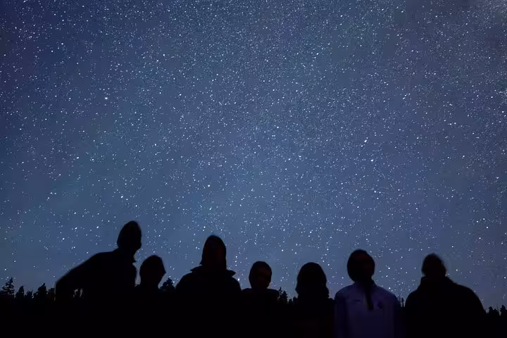 Group silhouettes watching a star-filled sky on a Bryce Canyon stargazing adventure in Utah dark sky park