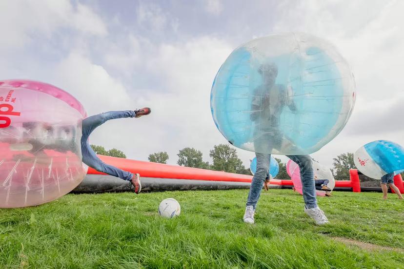 Friends collide in bubble suits on grass pitch during bubble football match in Weesp near Amsterdam