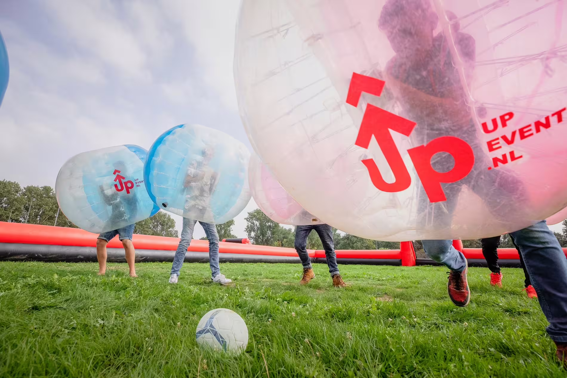 Bubble football match in Weesp with players in inflatable zorbs chasing a soccer ball on a grass field