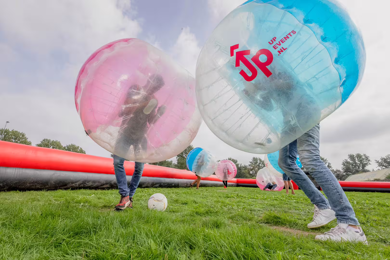 Players in inflatable bubble suits playing bubble football on grass in Weesp, Netherlands, fun group activity