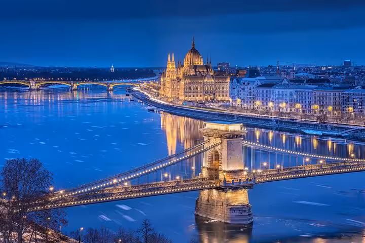 Chain Bridge and Hungarian Parliament lit at dusk on Budapest day trip from Vienna small-group tour