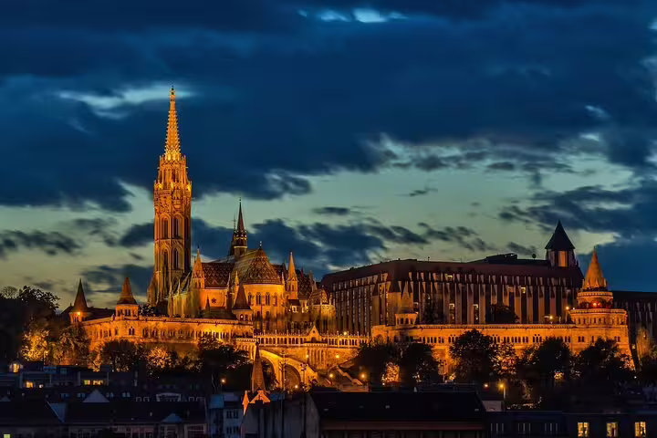 Stunning night view of Budapest's illuminated Fisherman's Bastion and Matthias Church under a dramatic evening sky.