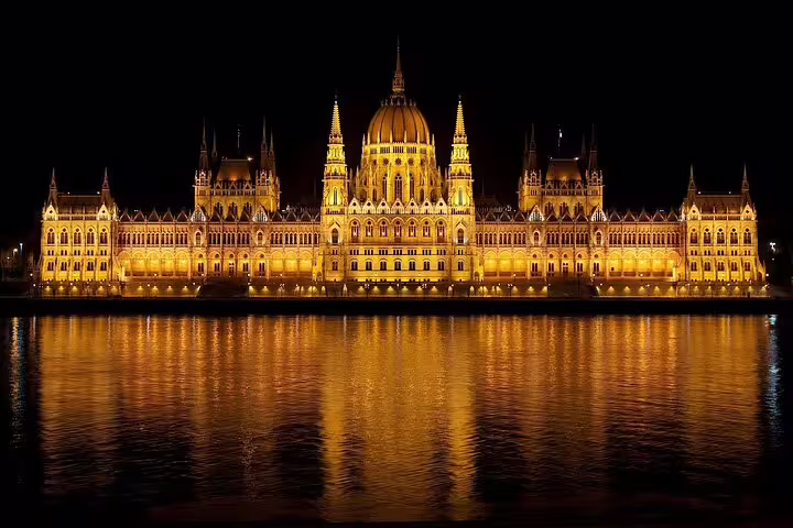 Stunning nighttime view of Budapest's illuminated Parliament building reflecting on the Danube River, highlighting its majestic architecture.