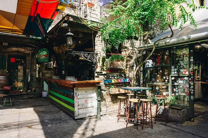 Outdoor courtyard ruin bar in Budapest with colorful bar counter, stools, and greenery on a walking tour