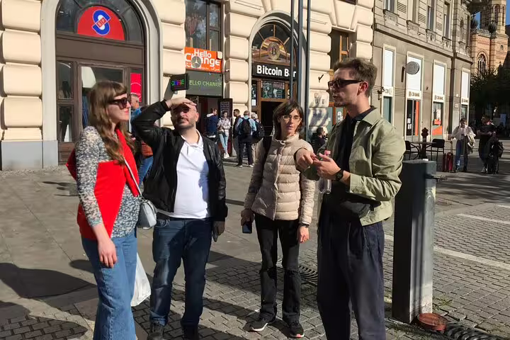 Guide briefing guests in downtown Budapest on a street art walking tour near metro entrance and murals