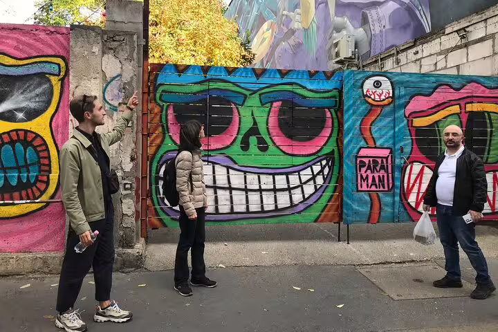 Budapest street art walking tour group viewing colorful graffiti wall with giant smiling face mural