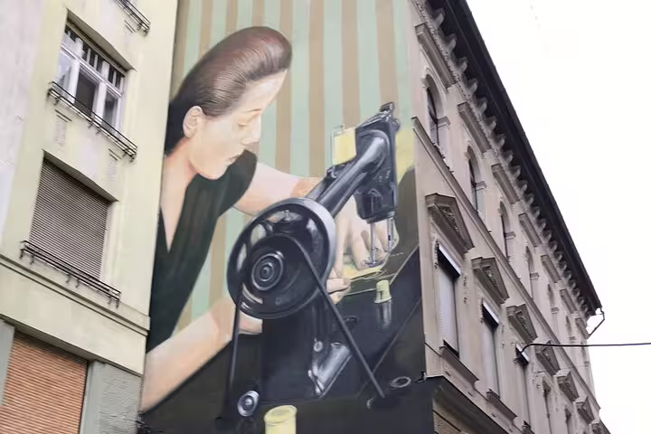 Budapest street art mural of woman sewing on building facade, highlight of urban graffiti walking tour